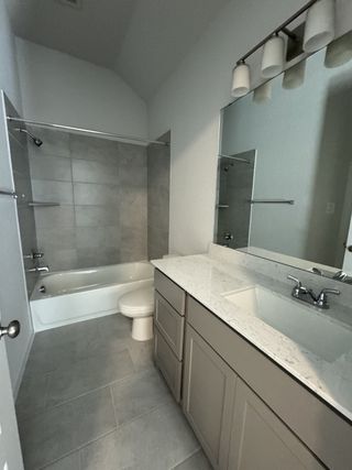 A modern bathroom featuring a sleek vanity, quartz countertops, a tiled shower, and elegant lighting for a stylish, contemporary feel.