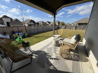A covered patio with stylish wicker seating overlooking a spacious backyard, perfect for outdoor relaxation.