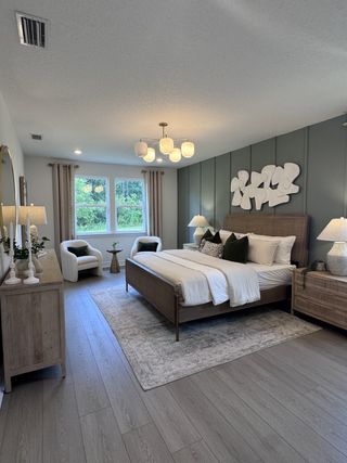 Model Home A contemporary bedroom with a wood bed frame, elegant lighting, and serene green accent wall.