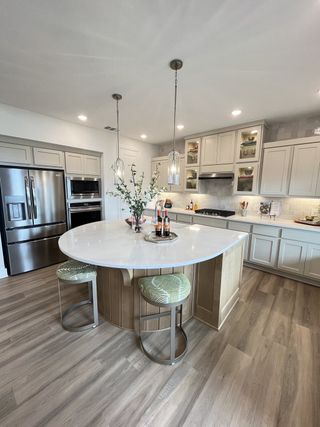 A modern kitchen featuring a rounded island, stainless steel appliances, and sleek wooden floors.
