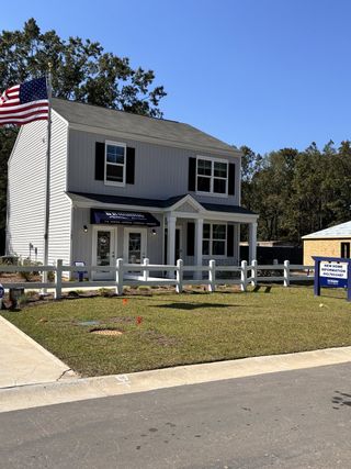 A charming two-story home with a fenced yard and flag in Back River Bend by D.R. Horton, Goose Creek, SC.