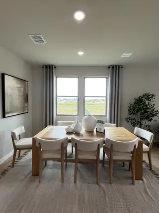 A contemporary dining area featuring a wooden table, elegant chairs, and large windows providing abundant natural light.