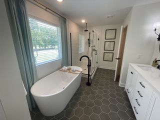 A modern bathroom featuring a freestanding tub, hexagonal tile flooring, and sleek fixtures with ample natural light.