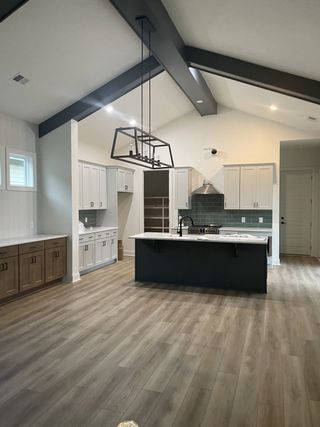 A modern kitchen with vaulted ceilings, a sleek island, wood cabinetry, and stylish lighting fixtures.