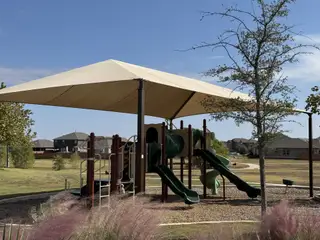 Community Amenities A shaded playground with green slides, perfect for family fun, in the Saddle Creek Twinhomes community by Pacesetter Homes (Georgetown, TX).