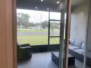 A cozy screened-in patio with wicker furniture, offering a relaxing outdoor space with views of the surrounding area.