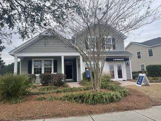 A charming gray home with a welcoming porch and manicured landscaping in Lindera Preserve at Cane Bay Plantation by Lennar (Summerville, SC).