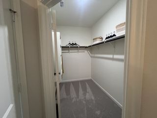 A spacious walk-in closet featuring ample shelving, hanging racks, and neutral carpeting for organized storage.