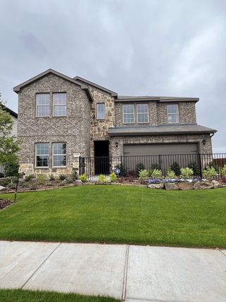 A beautiful stone and brick home with lush landscaping in Liberty Crossing by D.R. Horton (Royse City, TX).