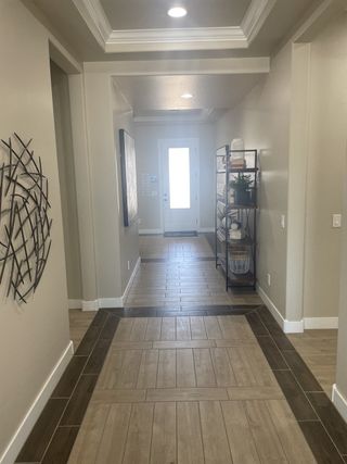 Model Home A modern hallway with elegant tile flooring, recessed lighting, and tasteful wall art.