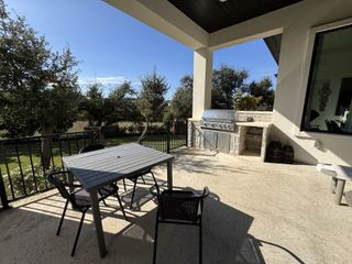 A spacious outdoor patio featuring a built-in grill, a dining set, and a view of the landscaped backyard, ideal for outdoor gatherings and relaxation.