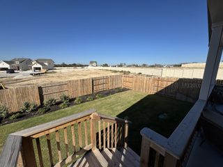 A sunlit backyard with a wooden fence and stairs overlooking a new development in Cannon Ranch 40s by Ashton Woods (Dripping Springs, TX).