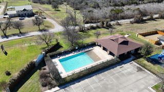 A community pool and clubhouse in Cloud Country by CastleRock Communities, New Braunfels, TX, surrounded by lush greenery.