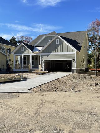 A charming green home under construction with a gable roof in Overlook at Copahee Sound by Dream Finders Homes (Awendaw, SC).