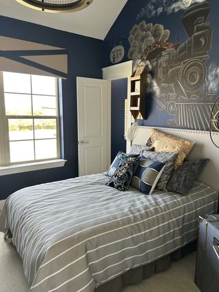 A cozy bedroom with blue walls, a stylish train mural, and striped bedding, adding charm and character to the space.