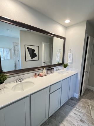 Model Home A contemporary bathroom with double sinks, sleek cabinetry, and modern decor, featuring elegant lighting and a huge mirror.