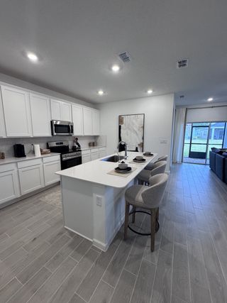 A modern kitchen with sleek white cabinets, a stylish island with seating, and elegant lighting.