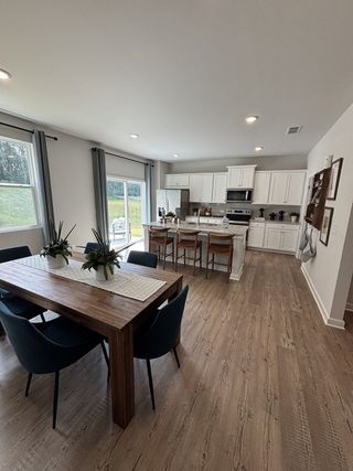 Spacious kitchen with sleek white cabinetry, wooden island seating, and a rustic dining table with modern navy chairs.