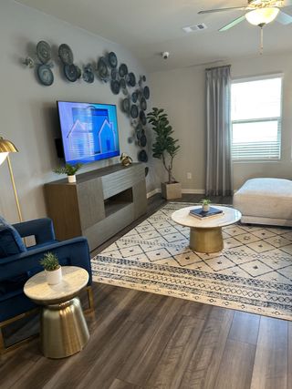 A cozy living room with warm wood flooring, bold wall decor, and chic furnishings, perfect for relaxing and entertaining.