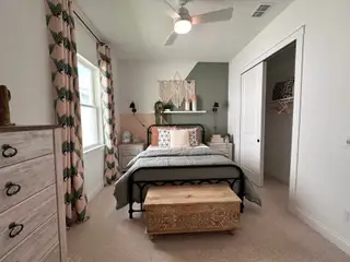 A cozy bedroom with patterned curtains, wooden furniture, and soft lighting, creating a serene and inviting atmosphere.