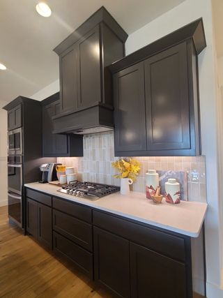 A modern kitchen with dark wood cabinets, white countertops, and light beige backsplash, featuring elegant decor elements.