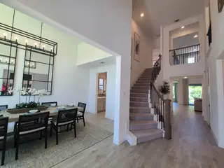 An elegant dining area and grand staircase with stylish decor and open layout.