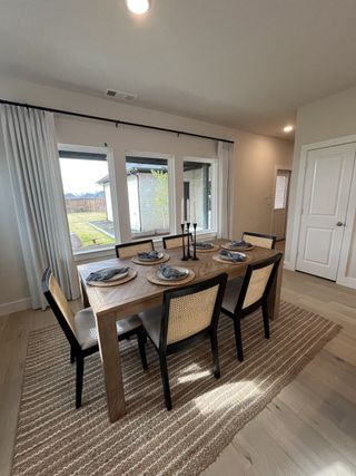 Model Home A stylish dining room with a wooden table, elegant table setting, and large windows overlooking the backyard.