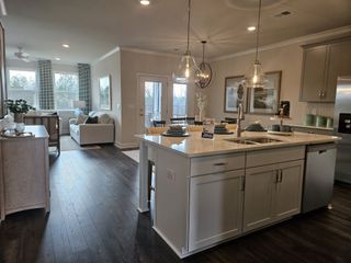 Model Home A modern open-concept kitchen with white cabinetry and stainless steel appliances in Oak Ridge Meadows by D.R. Horton (Locust Grove, GA).