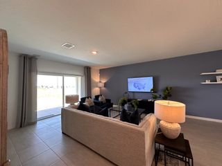 Model Home A modern living room featuring a cozy sofa, blue accent wall, and sleek decor, illuminated by natural light.