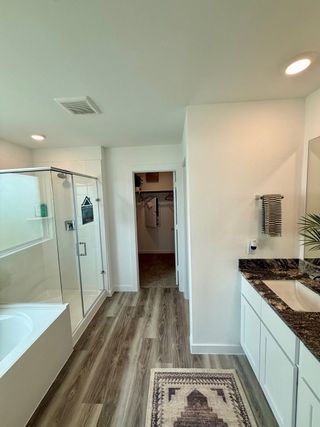 A modern bathroom with a glass-enclosed shower, granite countertop, elegant flooring, and cozy decor.