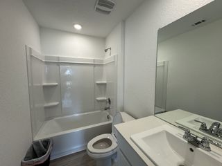 A modern bathroom featuring a classic white bathtub, sleek sink, and neutral decor with efficient lighting.