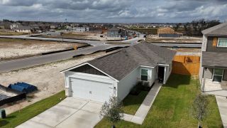 A modern white home with a two-car garage and fresh landscaping in Cool Water at Sonterra by LGI Homes (Jarrell, TX).