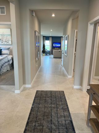 Model Home A modern hallway with tiled flooring, neutral tones, and an inviting view into a cozy living area.