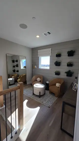 A cozy nook with modern armchairs, plank walls, and lush plants, perfect for relaxation and reading.