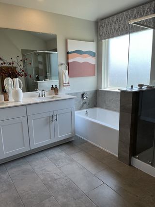 A modern bathroom features a sleek vanity, abstract wall art, spacious bathtub, and large mirror for a stylish look.