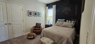 A cozy bedroom with a chalkboard wall, stylish decor, and a football-themed chair set for a sports enthusiast.