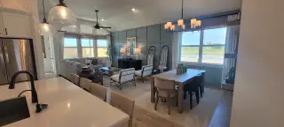 Open-concept living and dining area with large windows, contemporary furnishings, and soft lighting.