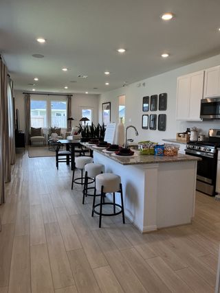 An open-concept kitchen and living area featuring sleek white cabinets, modern appliances, and stylish bar seating.