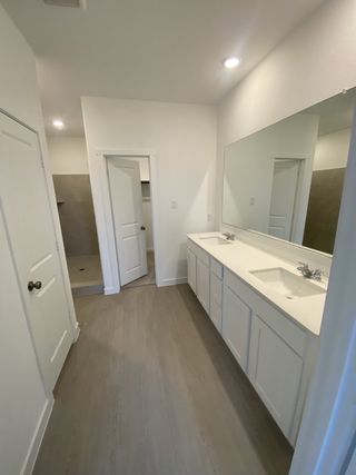 A sleek bathroom with dual sinks, soft wood flooring, and spacious shower area for a modern touch.