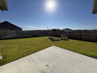Model Home A spacious, sunny backyard offers ample green space and a wooden fence, perfect for outdoor activities and privacy.