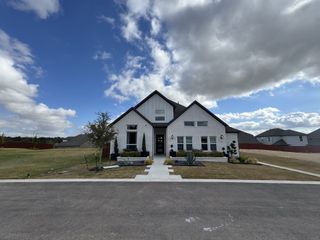 A modern white brick home with elegant landscaping in Sauls Ranch East by Coventry Homes, Round Rock, TX.