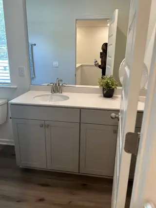 A modern bathroom with a sleek white vanity, elegant faucet, and soft natural light filtering through the window.