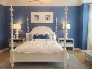 A luxurious bedroom featuring a four-poster bed, elegant blue accent walls, and chic decor elements.