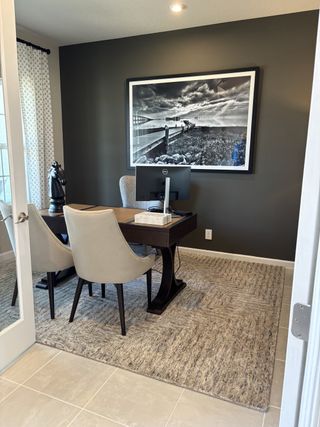 A modern office with sleek chairs, a dark accent wall, and monochrome art creating a cozy yet professional atmosphere.