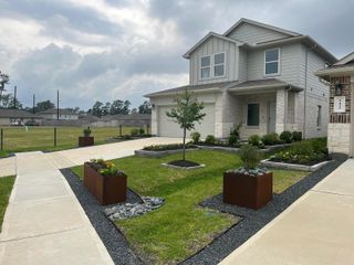 A beautifully landscaped two-story home with modern gray siding and stone accents in Breckenridge Forest by D.R. Horton (Spring, TX).