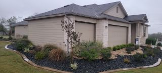 Street view A charming beige home with stone accents and lush landscaping in Summer Hills by M/I Homes (San Antonio, TX).