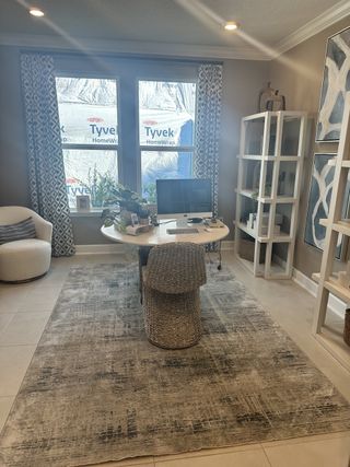 A cozy home office with a woven chair, patterned curtains, and decorative shelving for a stylish and functional workspace.