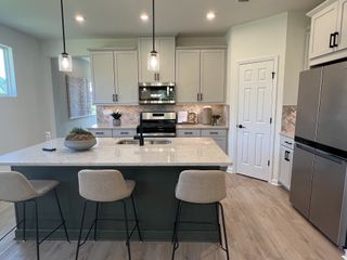A modern kitchen featuring a spacious island, sleek appliances, chic pendant lighting, and elegant cabinetry.
