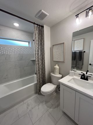  A well-lit bathroom with a bathtub, modern vanity, and elegant decor.