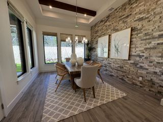 A stunning dining room featuring a textured brick accent wall, wood beams, and elegant lighting.
